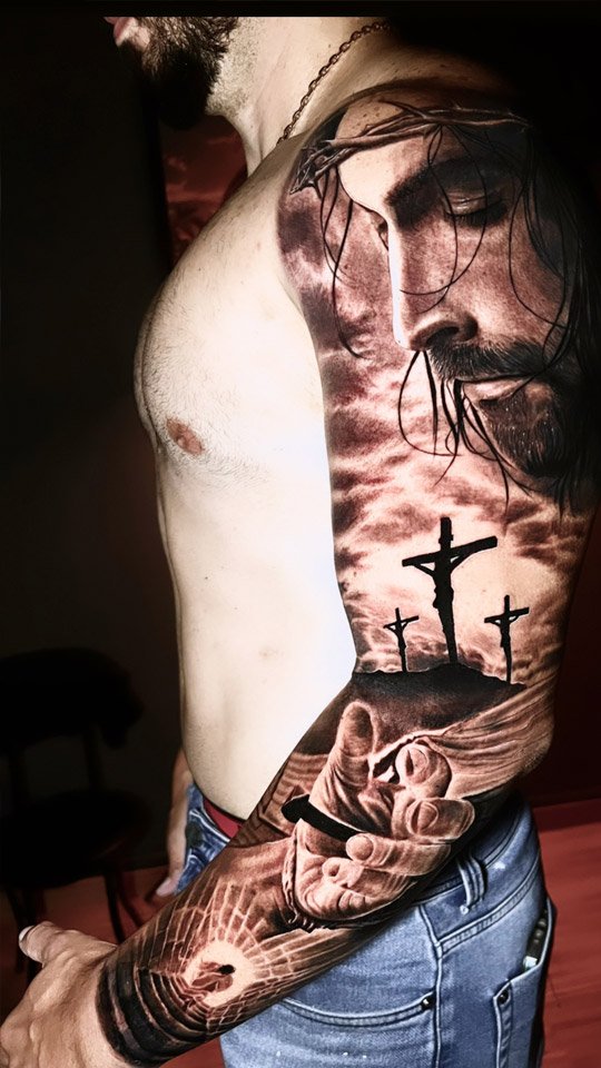 Braço fechado com rosto de Cristo, cruzes e paisagem em realismo preto e cinza